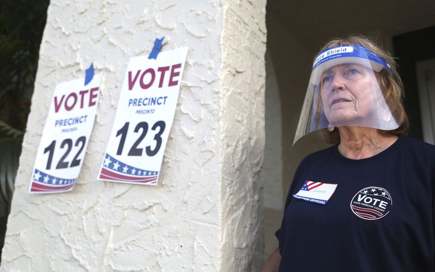Pinellas County poll worker Jeanne Coffey wears a protective shield as she worked the front door at the Coliseum Ball Room during the state's primary election, Tuesday, Aug. 18, 2020, in St. Petersburg, Fla. (Scott Keller/Tampa Bay Times via AP)