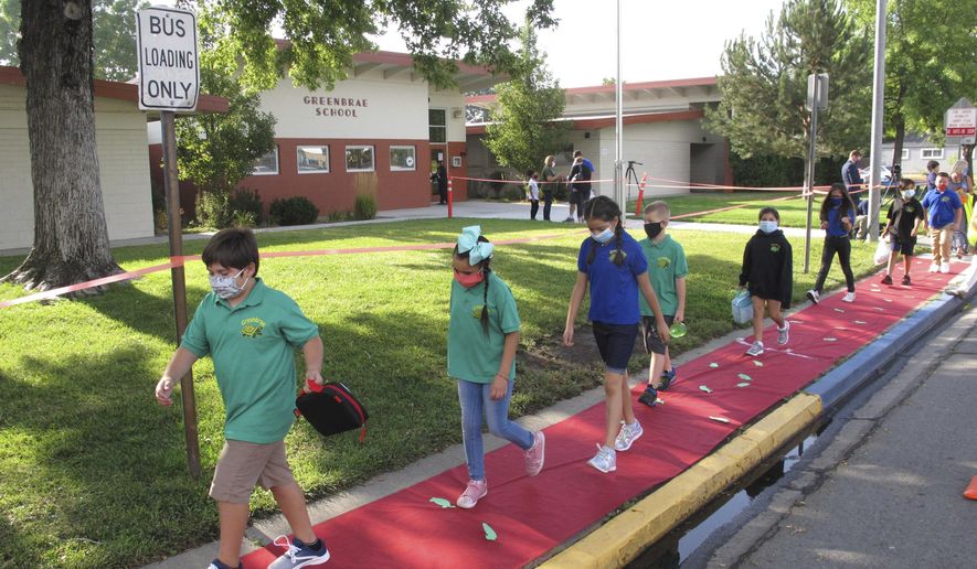 Students return to Greenbrae Elementary School in Sparks, Nev., on Tuesday, Aug. 18, 2020, for the first time since March with mandatory masks and social distancing to help guard against the spread of the coronavirus. Washoe County schools are using a combination of classroom instruction and distance learning. Nevada's largest school district resumes school in Las Vegas next week using strictly remote learning. (AP Photo/Scott Sonner).