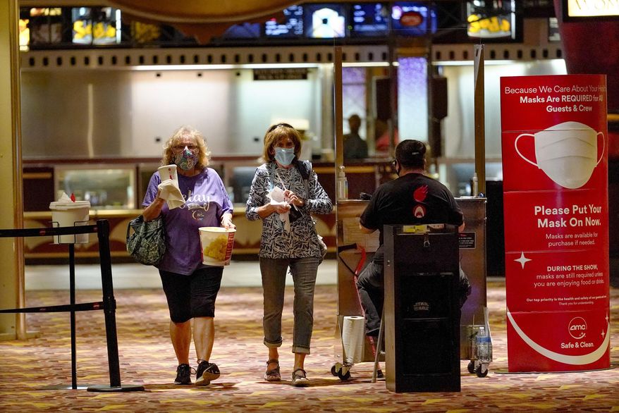 Betty Gallagher, left, carries popcorn and drinks beside Mary MacBeth as they pass by the ticket checkpoint, heading off to see, "I Still Believe", one of the first showings at the AMC theatre when it re-opened for the first time since shutting down at the start of the COVID-19 pandemic, Thursday, Aug. 20, 2020, in West Homestead, Pa. (AP Photo/Keith Srakocic)