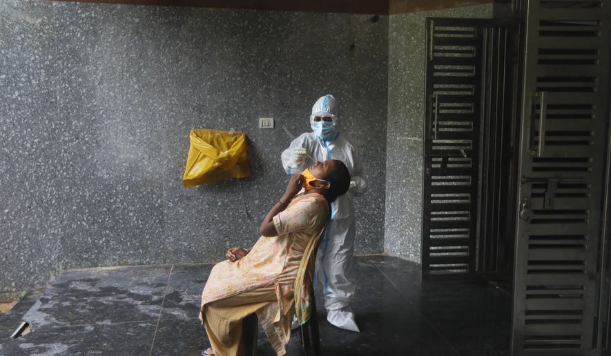 A health worker takes a nasal swab to test for COVID-19 in a government school in New Delhi, India, Thursday, Aug. 20, 2020. The country has the fourth-most deaths in the world and the third-most cases, with over 2.7 million, including more than 64,000 new infections reported Wednesday. (AP Photo/Manish Swarup)