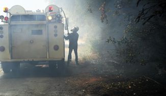 Jesse Katz pulls a hose from a vehicle carrying water while volunteering to fight the CZU August Lightning Complex Fire on Friday, Aug. 21, 2020, in Bonny Doon, Calif. Wildfires that have forced tens of thousands of people from their homes are still raging in California. (AP Photo/Marcio Jose Sanchez)