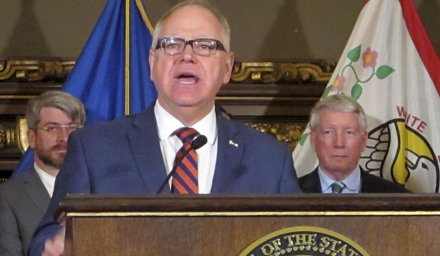 In this April 9, 2019 file photo, Minnesota Gov. Tim Walz, center, and Commerce Commissioner Steve Kelley, right, appear at a news conference at the state Capitol in St. Paul, Minn. Mr. Walz is the target of a lawsuit by businesses and churches which hope to overturn the state&#x27;s mask mandate. (AP Photo/Steve Karnowski File)