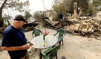 Hank Hanson, 81, looks at artificial flowers that remained standing as the LNU Lightning Complex fires destroyed his Vacaville, Calif., home on Friday, Aug. 21, 2020. Hanson, who built the house thirty years ago, does not think he will rebuild. (AP Photo/Noah Berger)