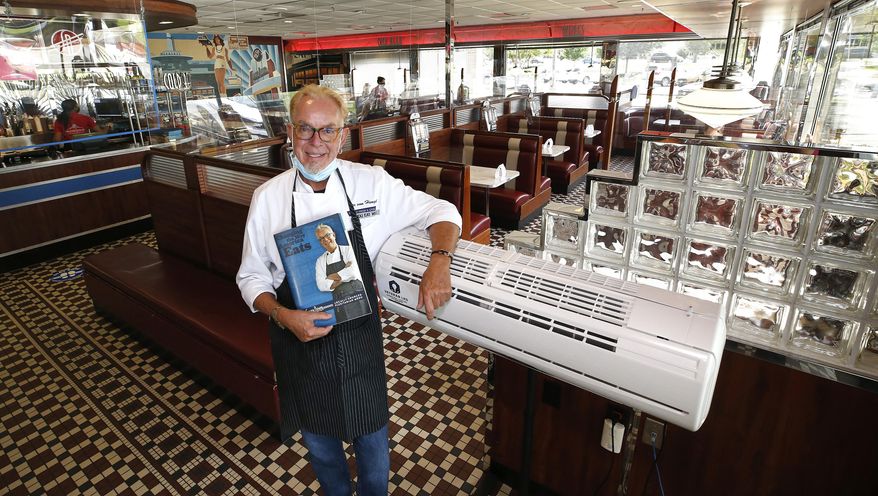 Chef Ype Von Hengst, co-founder and executive chef of the Silver Diner, poses by one of the germicidal uv-c lighting units he has in the restaurant to kill germs, Tuesday, Aug. 18, 2020, in Glen Allen, Va. The restaurant, which, on Aug. 12, became the first restaurant chain in the U.S. to install air filtration, purification and ultraviolet light systems across all its 18 locations in Virginia, Maryland and New Jersey, plus two Silver New American Brasseries. The menus are made of material that is easy to clean after each use. (Alexa Welch-Edlund/Richmond Times-Dispatch via AP)
