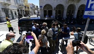Journalists and photographers are gathered in front of a van used to transport England footballer Harry Maguire as he leaves from the court on the Aegean island of Syros, Greece, on Saturday, Aug. 22, 2020. The Manchester United captain was arrested during a brawl on the neighbouring holiday island of Mykonos. (AP Photo/Michael Varaklas)
