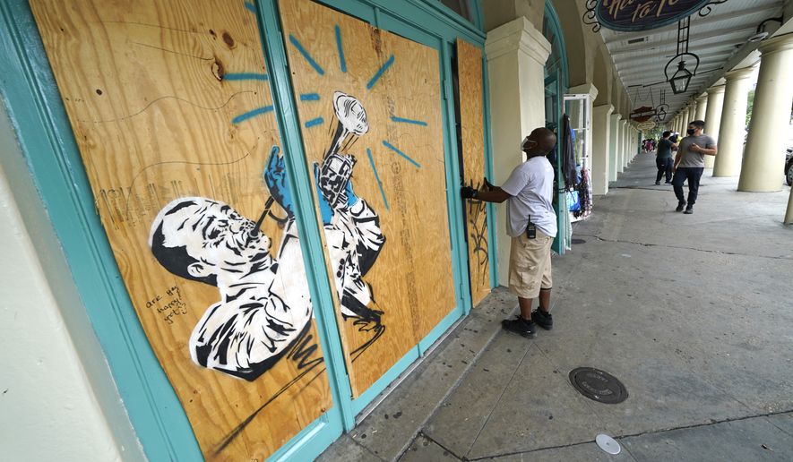 Workers board up shops in the French Quarter of New Orleans, Sunday, Aug. 23, 2020, in advance of Hurricane Marco, expected to make landfall on the Southern Louisiana coast. (AP Photo/Gerald Herbert)