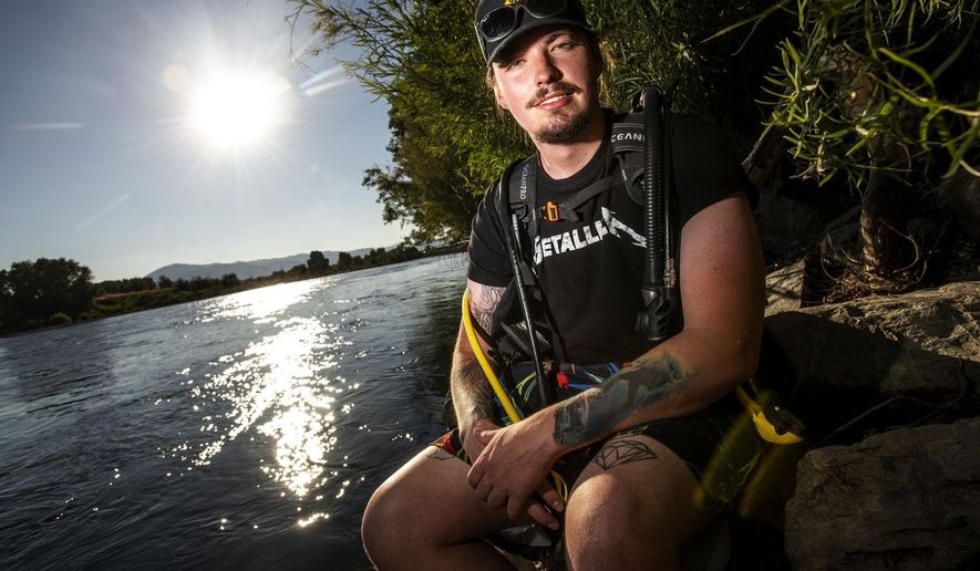 Seth Liston, who has been volunteering his time to retrieve trash left behind at Nimrod Hot Springs, poses Friday, Aug. 14, 2020, in Nimrod, Mont. Using his scuba diving gear, Liston has found broken glass, beer bottles and various other items left by those abusing the hot springs. (Ben Allan Smith/The Missoulian via AP)