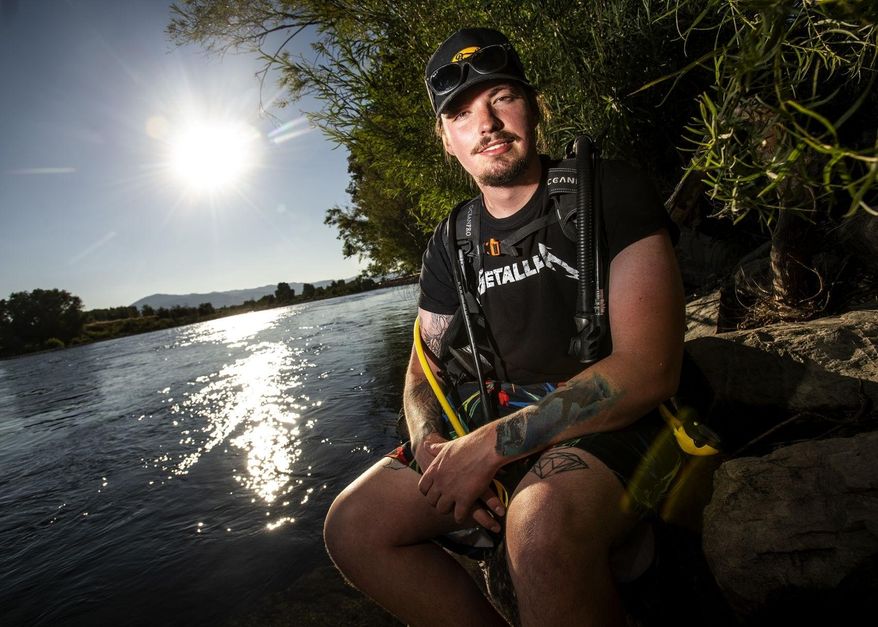Seth Liston, who has been volunteering his time to retrieve trash left behind at Nimrod Hot Springs, poses Friday, Aug. 14, 2020, in Nimrod, Mont. Using his scuba diving gear, Liston has found broken glass, beer bottles and various other items left by those abusing the hot springs. (Ben Allan Smith/The Missoulian via AP)