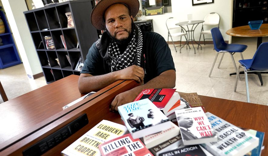 Owner Ali Nervis displays books on race relations at his bookstore Friday, Aug. 21, 2020 in Phoenix. Black-owned bookstores across the U.S. have seen increased sales following the police killings of Breonna Taylor and George Floyd, and store owners are now asking people who have read about Black history and culture to take action against the systems that have enabled racism. (AP Photo/Matt York)
