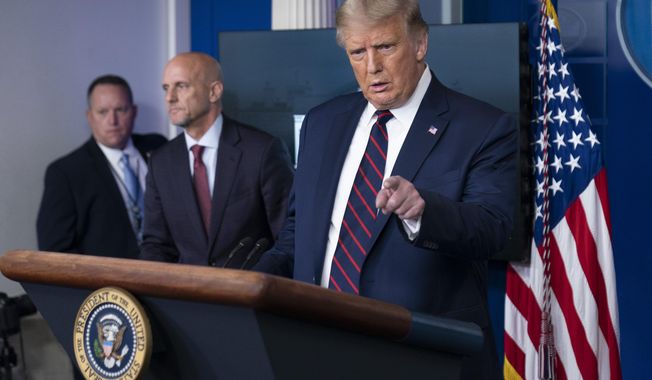 President Donald Trump speaks, accompanied by Food and Drug Administration Commissioner Dr. Stephen Hahn, center, during a media briefing in the James Brady Briefing Room of the White House, Sunday, Aug. 23, 2020, in Washington.(AP Photo/Alex Brandon)