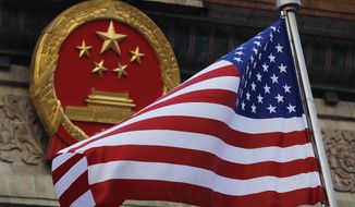 In this Nov. 9, 2017, photo, an American flag is flown next to the Chinese national emblem during a welcome ceremony for visiting U.S. President Donald Trump outside the Great Hall of the People in Beijing. (AP Photo/Andy Wong) **FILE**