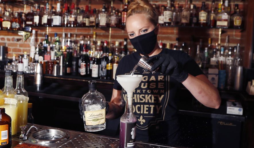 Sugar House bartender Shelby Minnix creates a Lavender Lemonade cocktail in a to-go bottle, Thursday, Aug. 13, 2020, in Detroit. At least 33 states and the District of Columbia are temporarily allowing cocktails to-go during the pandemic, up from around three before the coronavirus struck. Dave Kwiatkowski, who owns the Sugar House was able to reopen July 10 for carryout service. Kwiatkowski normally employs a staff of 16, but for now, it's just him at the door and a bartender making drinks. (AP Photo/Carlos Osorio)