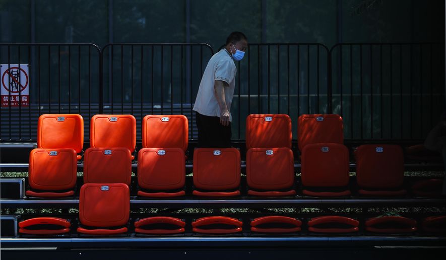 A worker wearing a face mask to help curb the spread of the coronavirus cleans the seats at a basketball court in Beijing, Monday, Aug. 24, 2020. China has gone eight days without reporting a new local case of COVID-19, with the Beijing International Film Festival among public events that are returning. (AP Photo/Andy Wong)