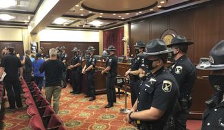 Idaho State Police form a row in a committee meeting room in the Idaho Statehouse in Boise, Idaho, on Tuesday, Aug. 25, 2020. One person was taken into custody and lawmakers abandoned the room after spectators at a House committee meeting at the Idaho Statehouse became disruptive. The committee left the room as at least a dozen Idaho State Police formed a shield between them and the crowd of more than 100. (AP Photo/Keith Ridler)