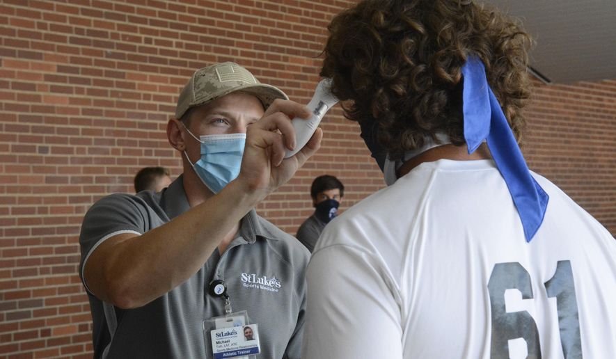 Michael Toth, athletic trainer, left, takes Gavin Guers' temperature before football practice at Blue Mountain High School in Orwigsburg, Pa., on Monday, Aug. 24, 2020. (Lindsey Shuey/The Republican-Herald via AP)