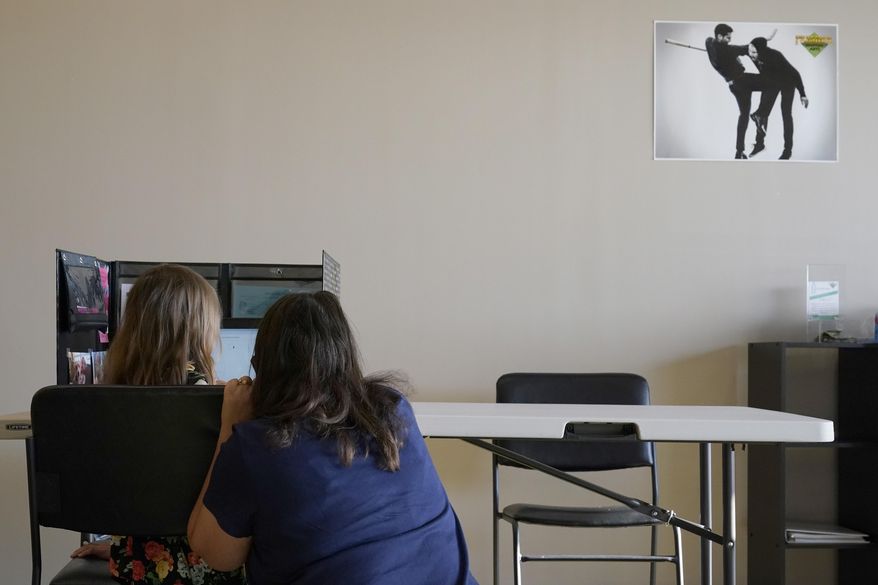 Audra Quisenberry, 6, gets help setting up Zoom on her computer from Julie McMillen,right, inside Premier Martial Arts on Audra's first day of school Monday, Aug. 24, 2020, in Wildwood, Mo. The first grader will attend her classes virtually while spending her days at the martial arts studio since her school has been shutdown due to the COVID-19 outbreak. (AP Photo/Jeff Roberson)