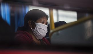 A woman who tested positive for COVID-19 waits  in a bus prior to her admission to a former students residence being used to quarantine asymptomatic patients infected with the new coronavirus in Caracas, Venezuela, Tuesday, Aug 25, 2020. (AP Photo/Ariana Cubillos)