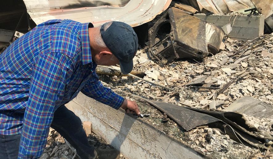 Charles Christianson, a 67-year-old retired school teacher goes through remains at his destroyed home after damage from a wildfire in Guerneville, Calif. on Tuesday, Aug. 25, 2020. (AP Photo/Aron Ranen)