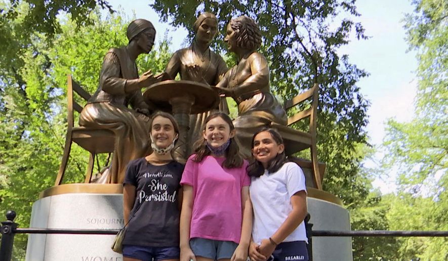Jaya Shri, 13, , right stands with friends at the unveiling of a new statue honoring suffragettes in Central Park on Wednesday, Aug. 26, 2020. bronze statue depicting women’s rights pioneers Sojourner Truth, Elizabeth Cady Stanton and Susan B. Anthony was unveiled in Central Park on Wednesday. It's the 167-year-old park’s first monument honoring real historical women — as opposed to fictional heroines like Alice in Wonderland and Shakespeare’s Juliet. (AP Photo/Ted Shaffrey)