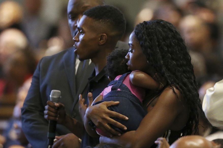 FILE - In this June 18, 2019 file photo Dravon Ames, holding microphone, speaks to Phoenix Police Chief Jeri Williams and Phoenix Mayor Kate Gallego, as his fiancee, Iesha Harper, right, holds 1-year-old daughter London, at a community meeting, in Phoenix. The Phoenix City Council will vote Wednesday, Aug. 26, 2020 on a settlement for the Black couple who had police officers point guns at them in front of their children last year after their young daughter took a doll from a store without their knowledge. (AP Photo/Ross D. Franklin, File)
