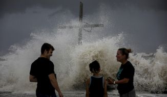 People talk as waves wash ashore and the outer bands of Hurricane Laura bring winds and rain Wednesday, Aug. 26, 2020, in High Island. ( Jon Shapley/Houston Chronicle via AP)