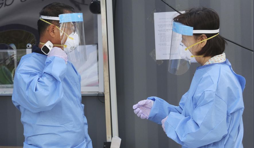 A medical worker measures his own body temperature during the COVID-19 testing at a makeshift clinic in Seoul, South Korea, Wednesday, Aug. 26, 2020. Health officials in South Korea called on thousands of striking doctors to return to work as the country counted its 13th straight day of triple-digit daily jumps in coronavirus cases.(AP Photo/Ahn Young-joon)