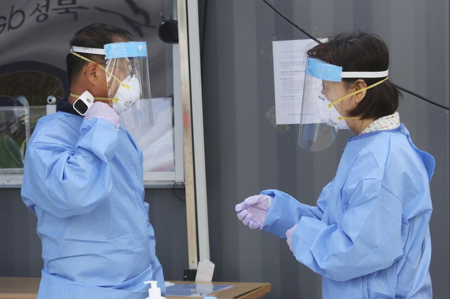 A medical worker measures his own body temperature during the COVID-19 testing at a makeshift clinic in Seoul, South Korea, Wednesday, Aug. 26, 2020. Health officials in South Korea called on thousands of striking doctors to return to work as the country counted its 13th straight day of triple-digit daily jumps in coronavirus cases.(AP Photo/Ahn Young-joon)