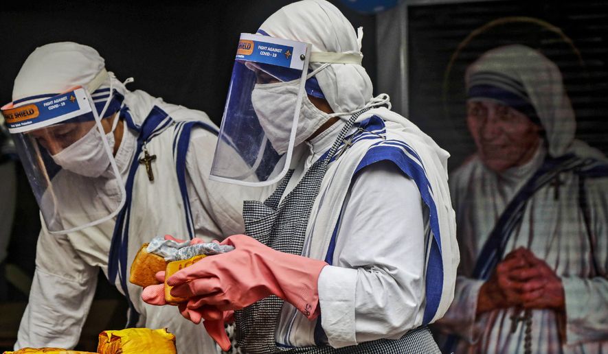 Nuns of the Missionaries of Charity, the order founded by Saint Teresa, wearing masks and face shields as precaution against the coronavirus distribute food to poor and homeless people in Kolkata, India, Wednesday, Aug. 26, 2020. Wednesday marked the birth anniversary of Nobel laureate Mother Teresa, a Catholic nun who spent 45-years serving the poor, the sick, the orphaned, and the dying. (AP Photo/Bikas Das)