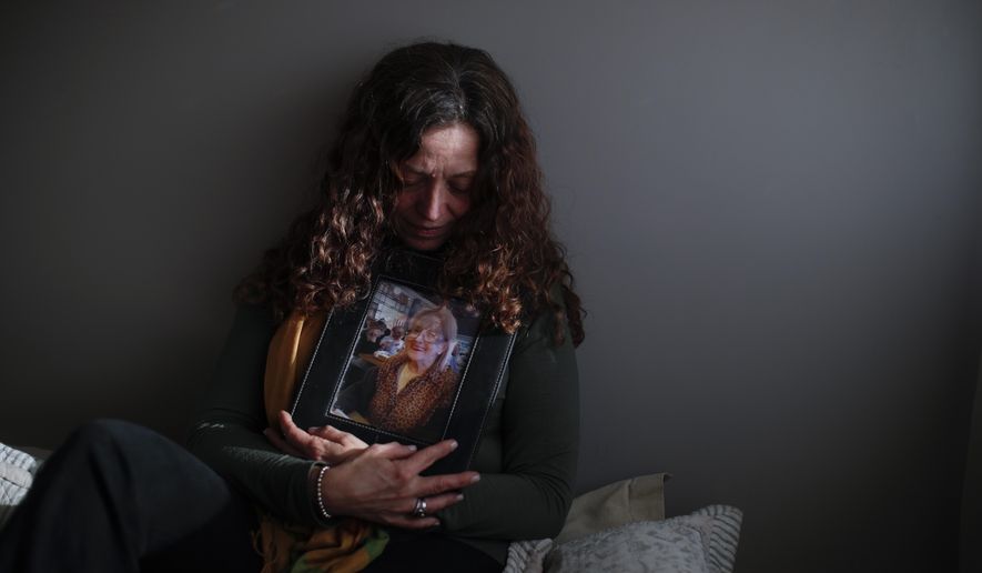Fernanda Mariotti cradles a picture of her mother Martha Pedrotti, who passed away a victim of COVID-19, at her home in Buenos Aires, Argentina, Tuesday, Aug. 11, 2020. Mariotti believes that her mother eventually died in part from a heart condition and also from the sorrow and fear of being separated from her family, isolated in the COVID unit. (AP Photo/Natacha Pisarenko)