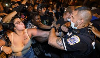Metropolitan Police are confronted by protestors as police carry away a handcuffed protestor along a section of 16th Street, Northwest, renamed Black Lives Matter Plaza, Thursday night , Aug. 27, 2020, in Washington, after President Donald Trump had finished delivering his acceptance speech from the White House South Lawn. (AP Photo/Julio Cortez)
