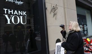 FILE - In this Jan. 2, 2019 file photo, a woman, who declined to give her name, pauses to take a photo of a sign outside Lord &amp;amp; Taylor&#39;s flagship Fifth Avenue store which closed its doors for good after a months-long blowout sale, in New York. Lord &amp;amp; Taylor, one of the country’s oldest department stores, is going out of business after filing for bankruptcy earlier this month. It will close its remaining 38 stores and shut down its website, the company said Thursday, Aug. 27, 2020.   (AP Photo/Kathy Willens, File)