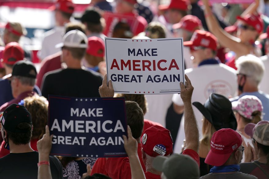In this Aug. 28, 2020, file photo people hold up campaign signs as they wait for a rally for President Donald Trump to begin at Manchester-Boston Regional Airport in Londonderry, N.H. (AP Photo/Charles Krupa, File)