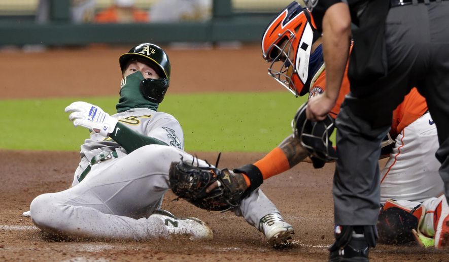 Oakland Athletics' Mark Canha, left, is out at the plate on a tag by Houston Astros catcher Martin Maldonado during the second inning of the first baseball game of a doubleheader Saturday, Aug. 29, 2020, in Houston. (AP Photo/Michael Wyke)