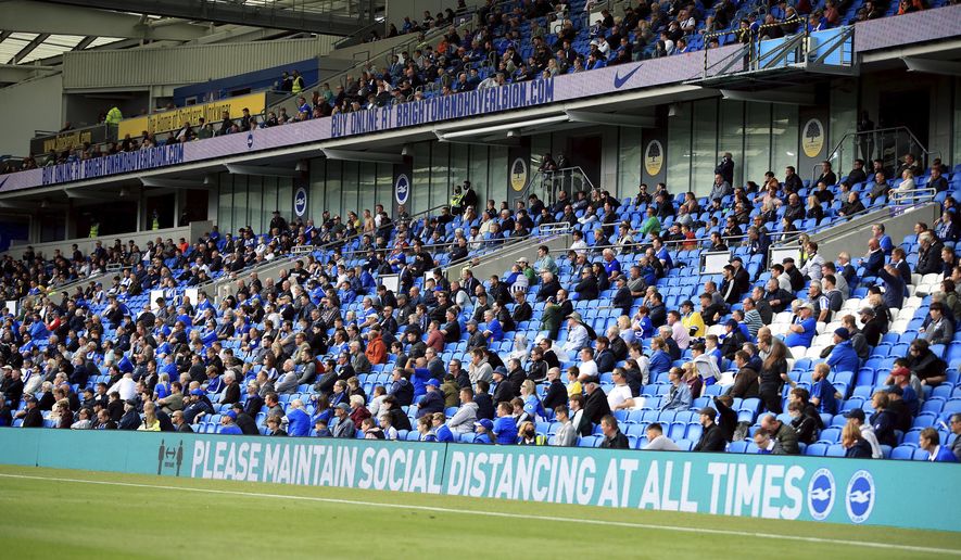 Brighton soccer fans adhere to social distancing measures in the stands as they watch the action on the pitch during the pre-season friendly between Brighton and Chelsea, at the AMEX Stadium in Brighton, England, Saturday, Aug. 29, 2020. Up to 2500 fans have been allowed in to watch the match after the government announced a further batch of sporting events that will be used to pilot the safe return of spectators. (Adam Davy/PA via AP)