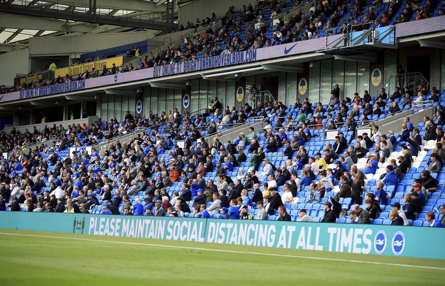 Brighton soccer fans adhere to social distancing measures in the stands as they watch the action on the pitch during the pre-season friendly between Brighton and Chelsea, at the AMEX Stadium in Brighton, England, Saturday, Aug. 29, 2020. Up to 2500 fans have been allowed in to watch the match after the government announced a further batch of sporting events that will be used to pilot the safe return of spectators. (Adam Davy/PA via AP)