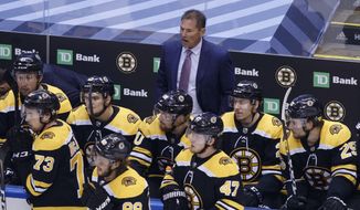 Boston Bruins head coach Bruce Cassidy, rear watches during the third period of an NHL hockey Stanley Cup playoff game against the Tampa Bay Lightning in Toronto, Saturday, Aug. 29, 2020. (Cole Burston/The Canadian Press via AP)