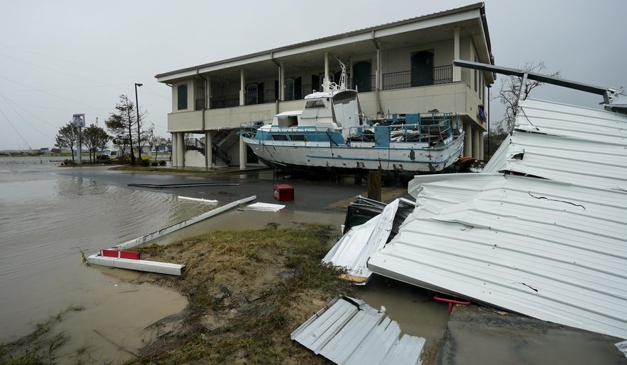 Flooding surrounds a damaged building and boat Friday, Aug. 28, 2020, in Cameron, La., after Hurricane Laura moved through the area Thursday. (AP Photo/David J. Phillip)