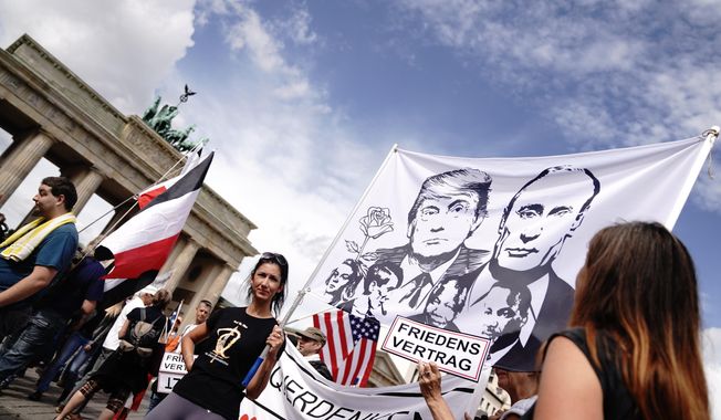 Participants gather at the Brandenburg Gate for a demonstration against the Corona measures and hold a banner with the picture of US President Trump and Russian President Putin in Berlin, Germany, Saturday, Aug. 29, 2020. (Kay Nietfeld/dpa via AP) **FILE**