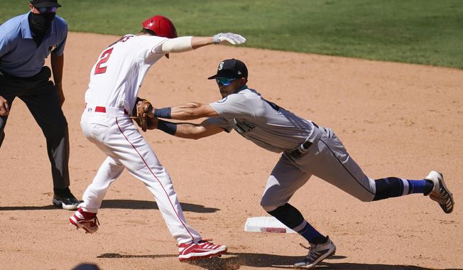 Los Angeles Angels&#x27; Andrelton Simmons, front left, is tagged out by Seattle Mariners third baseman Sam Haggerty in a rundown between first and second base during the seventh inning of a baseball game Sunday, Aug. 30, 2020, in Anaheim, Calif. Simmons drove in Albert Pujols with a single on the play. (AP Photo/Marcio Jose Sanchez)