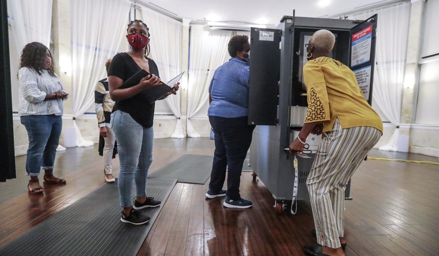 FILE - In this Tuesday, Aug. 11, 2020, file photo, poll workers prepare voting machines at Park Tavern amid the coronavirus pandemic, in Atlanta. A federal judge has ordered Georgia to extend its deadline for accepting mail-in ballots for November’s general election from the close of polls on Election Day until three days later. The secretary of state's office says it plans to immediately appeal the ruling. (John Spink/Atlanta Journal-Constitution via AP, File)