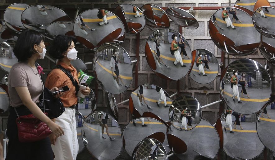 People wearing face masks to help protect against the spread of the coronavirus are reflected in mirrors at a subway station in Seoul, South Korea, Monday Aug. 31, 2020. South Korea has counted its 18th straight day of triple-digit daily jumps in coronavirus cases as its health minister warned about an increase in transmissions gone untraced.(AP Photo/Ahn Young-joon)