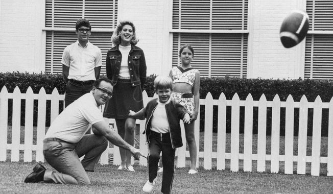 FILE - In this June 1, 1970, file photo, Kansas City Chiefs owner Lamar Hunt watches after holding the ball for his son, Clark, 5, to kick in the family backyard in Dallas. Behind them is Hunt&#x27;s children by a former marriage, Lamar Jr. 13, left, and Sharon, 12, right. His wife Norma is at center rear. Lamar Hunt was a champion of Black rights during the Civil Rights era of the 1960s. He grew up in conservative circles yet formed his own opinions of right and wrong. And when his football-loving son was born in 1965, those principles that Hunt instilled in his football franchise became instilled in Clark, who years later would take succeed him as chairman of the Chiefs. (AP Photo/File)