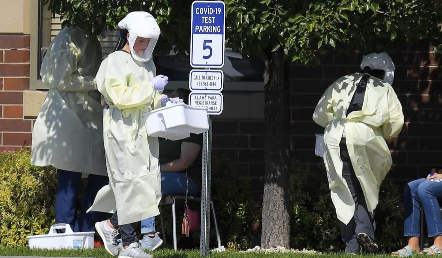 Workers test Utah State University students for COVID-19 on Sunday, Aug. 30, 2020, in Hyde Park, Utah. Students from four dorms were tested and quarantined after the virus was detected in the wastewater from those buildings. (Eli Lucero/The Herald Journal via AP)