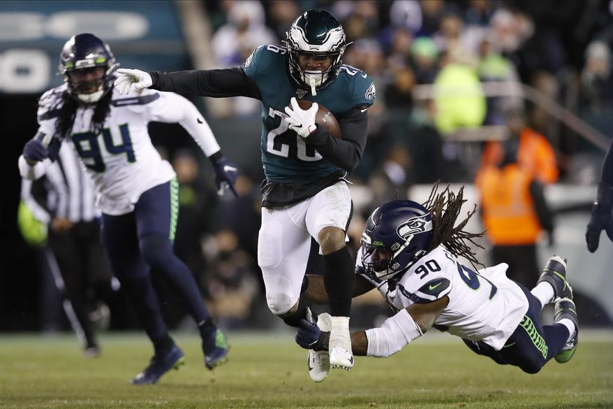 FILE - In this Sunday, Jan. 5, 2020 file photo, Philadelphia Eagles' Miles Sanders (26) tries to run past Seattle Seahawks' Jadeveon Clowney (90) during the first half of an NFL wild-card playoff football game against the Seattle Seahawks in Philadelphia. Miles Sanders shared running duties with Jordan Howard last season and still led all rookies in scrimmage yards, setting a Philadelphia Eagles franchise record in the category. He’ll be the go-to guy in the backfield this year. Sanders is one of the league's rising stars. (AP Photo/Julio Cortez, File)
