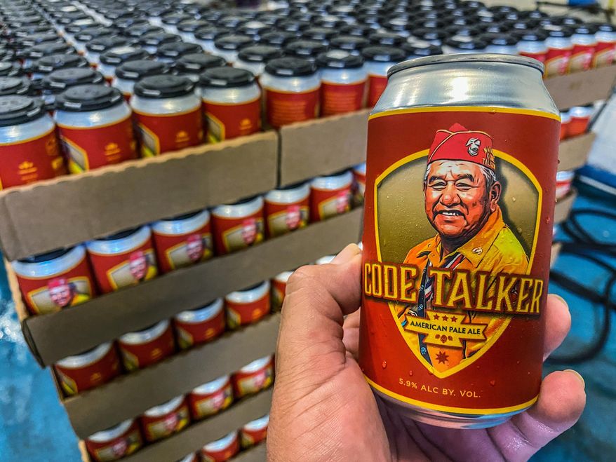 In this Aug. 14, 2020, photo courtesy of LT Goodluck, LT Goodluck holds a beer can honoring his grandfather, Navajo Code Talker John V. Goodluck at the Hellbender Brewing Co., in Washington, D.C. In honor of National Navajo Code Talkers Day the craft brewery recently rereleased its Code Talker American Pale Ale , this time in a can, drawing some rave reviews but also backlash. The beer was formulated and brewed by Goodluck in honor of his late grandfather and Navajo Code Talker John V. Goodluck. (LT Goodluck via AP)