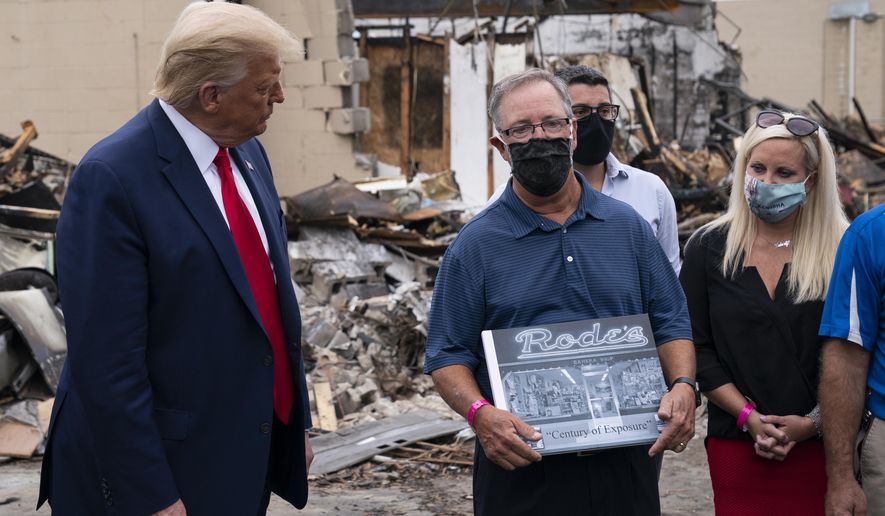 President Donald Trump talks with John Rode, the former owner of Rode’s Camera Shop, as he speaks with business owners Tuesday, Sept. 1, 2020, during a tour of an area damaged during demonstrations after a police officer shot Jacob Blake in Kenosha, Wis. (AP Photo/Evan Vucci) (CORRECTS TO SAY THAT JOHN RODE IS NOT THE CURRENT OWNER OF RODE’S CAMERA SHOP; HE IS THE FORMER OWNER)