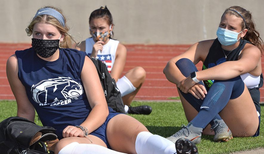 With face masks in place to slow the spread of COVID-19, Harbor Creek High School soccer players Haylee Wilson, 17, left, and Ali Tobin, 18, right, listen to Harbor Creek School District Superintendent Kelly Hess, not pictured, Monday, Aug. 24, 2020, at Paul J. Weitz stadium in Harborcreek Township, Erie County, Pennsylvania prior to the first day of official high school sports practices across the state. Athletes in Pennsylvania are allowed to remove face masks once they begin practicing or playing. (Christopher Millette/Erie Times-News via AP)