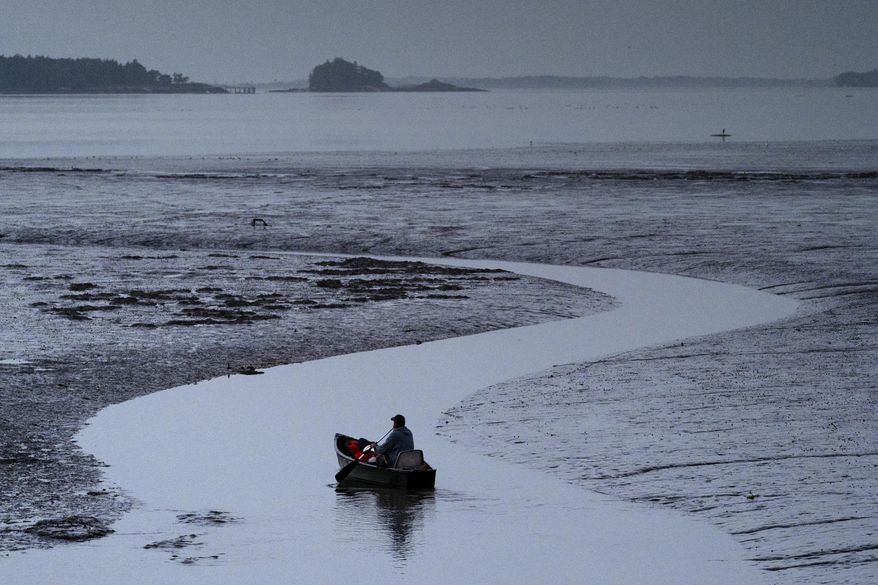 Clam digger Scott Lavers paddles his canoe on his way to work on a mudflat exposed by the receding tide at dawn, Friday, Sept. 4, 2020, in Freeport, Maine. (AP Photo/Robert F. Bukaty)