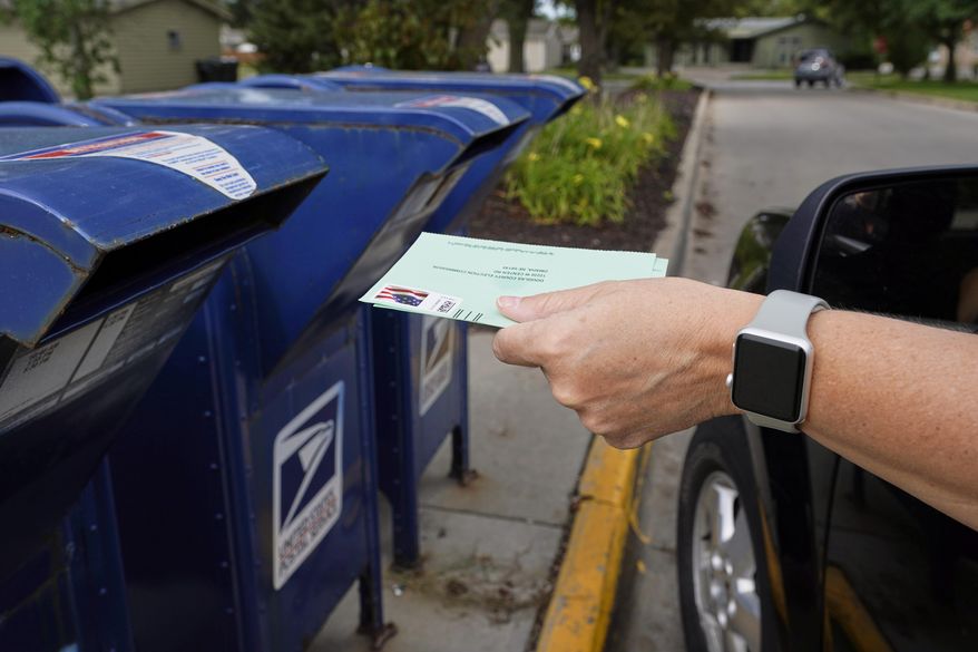 In this Tuesday, Aug. 18, 2020, file photo, a person drops applications for mail-in-ballots into a mailbox in Omaha, Neb. (AP Photo/Nati Harnik, File)