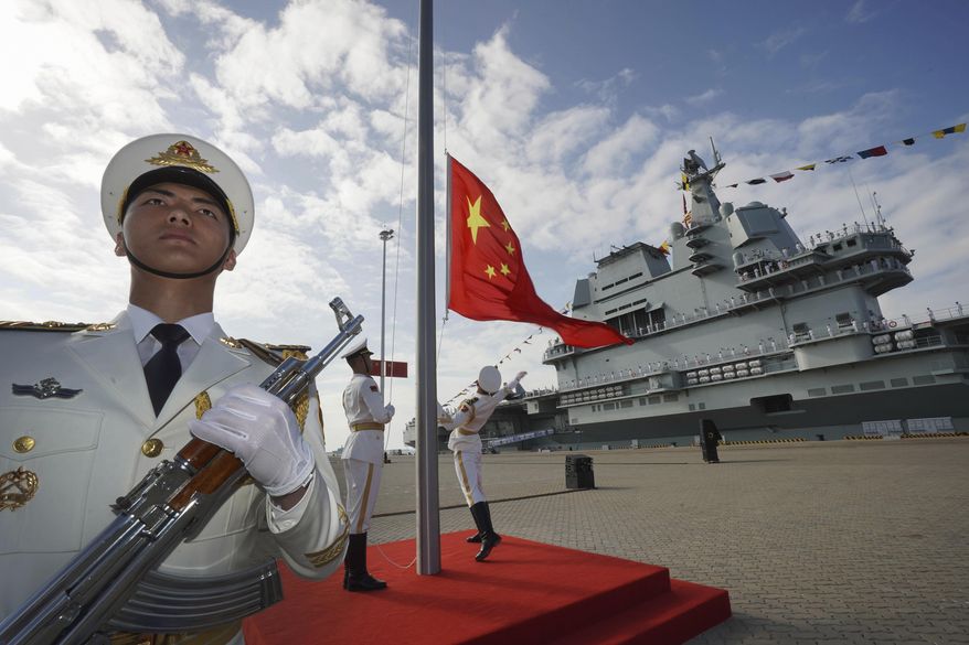 In this Dec. 17, 2019, file photo and released by Xinhua News Agency, Chinese honor guard raise the Chinese flag during the commissioning ceremony of China's Shandong aircraft carrier at a naval port in Sanya, south China's Hainan Province. Seventy-five years after Japan's surrender in World War II, and 30 years after its economic bubble popped, the emergence of a 21st-century Asian power is shaking up the status quo. As Japan did, China is butting heads with the established Western powers, which increasingly see its growing economic and military prowess as a threat. (Li Gang/Xinhua via AP) **FILE**
